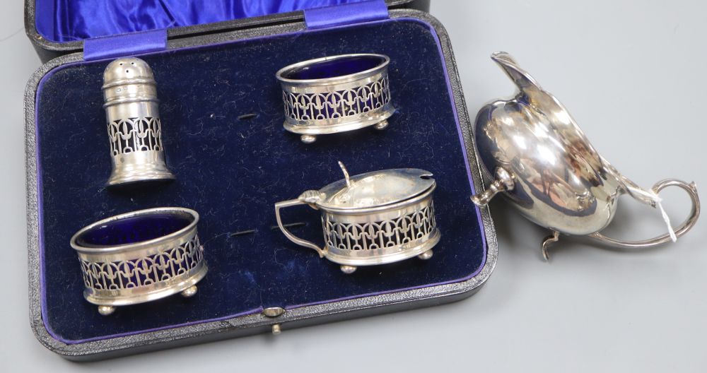 A cased four piece silver cruet set, Birmingham 1921, blue glass liners and a silver milk jug, 3.8oz.